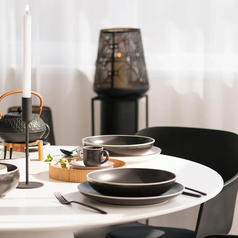 Prostřený stůl s černým porcelánem, konvicí a lucernou